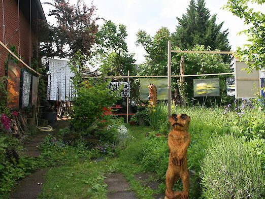 Verschiedenen Kunstgegenstände in einem Garten. Im Vordergrund ein Bärenstatue.